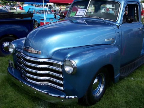 1972 Ford Ranchero - A bright blue Chevrolet pickup truck is displayed at an outdoor car show, with other vehicles visible in the background.
