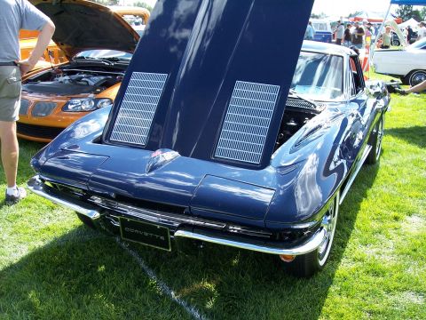 1972 Ford Ranchero - A dark blue Chevrolet Corvette is displayed with its hood open at an outdoor car show, with another car visible in the background.