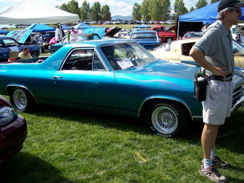 1972 Ford Ranchero - A teal 1970 El Camino is displayed at a car show with other vehicles and tents in the background.