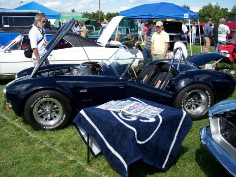 1972 Ford Ranchero - A dark blue convertible sports car is displayed with its hood open at an outdoor car show.