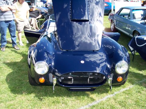 1972 Ford Ranchero - A dark blue sports car is displayed with its hood open at an outdoor event.