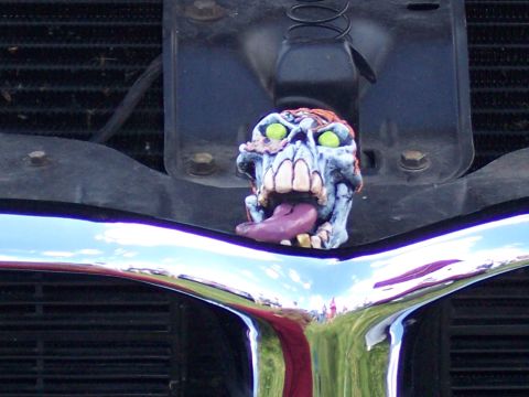 1972 Ford Ranchero - A bizarre monster figurine adorns the chrome grille of a vehicle, reflecting the surrounding environment.