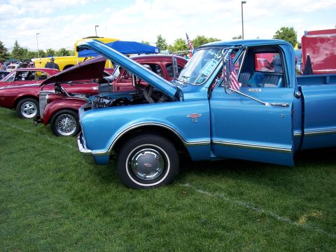 1972 Ford Ranchero - A line of classic vehicles are displayed on a grassy field under a partly cloudy sky.