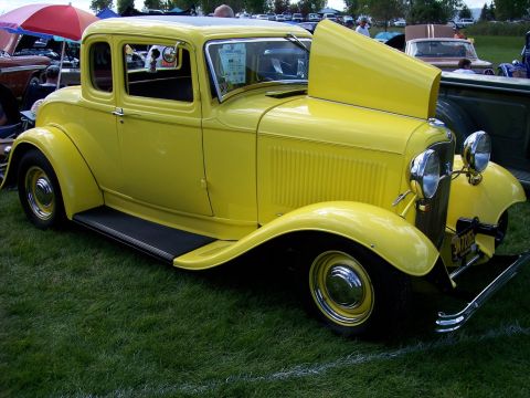 1972 Ford Ranchero - A bright yellow hot rod coupe is displayed at an outdoor car show with its hood open.