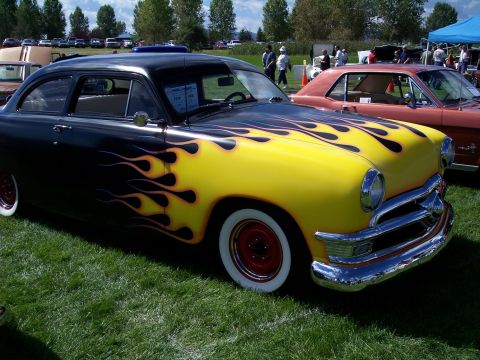 1972 Ford Ranchero - A customized 1950s coupe with flame paintwork is displayed at an outdoor car show.