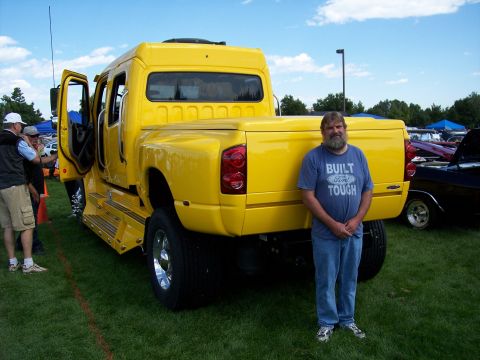 1972 Ford Ranchero - A man stands next to a bright yellow custom truck at an outdoor event.