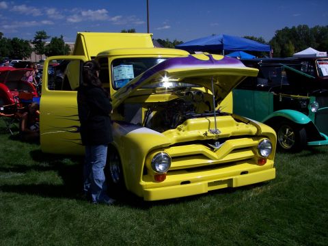 1972 Ford Ranchero - A yellow 1956 Ford F-100 pickup truck is displayed with its hood open at an outdoor car show.