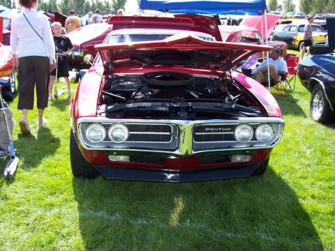 1972 Ford Ranchero - A red 1969 Pontiac Firebird is displayed with its hood open at an outdoor car show.