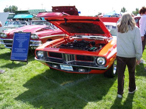 1972 Ford Ranchero - An orange 1970 Plymouth Barracuda is displayed with its hood open, parked on grass next to other vehicles.