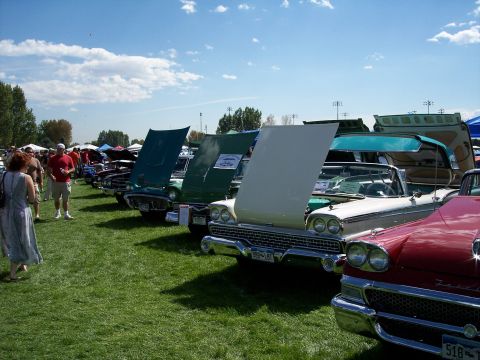 1972 Ford Ranchero - Several vintage automobiles are parked on a grassy field under a blue sky with clouds.