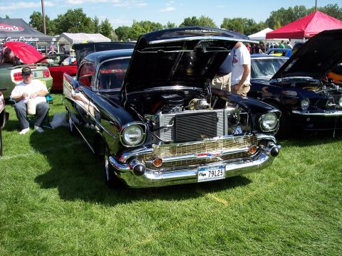 1972 Ford Ranchero - A classic black 1957 Chevrolet Bel Air is displayed with its hood open at an outdoor car show.