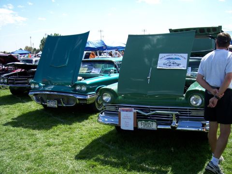 1972 Ford Ranchero - Two classic Ford Fairlanes from 1957 are displayed with their hoods open at an outdoor car show.