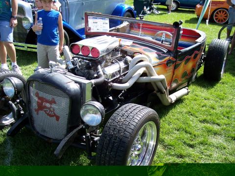 1972 Ford Ranchero - A custom hot rod with flame paint and a prominent engine is displayed at an outdoor event.