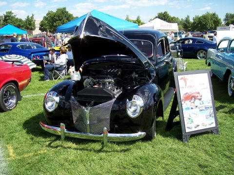 1972 Ford Ranchero - A black 1940 Ford Deluxe sedan is displayed with its hood open at an outdoor car show.
