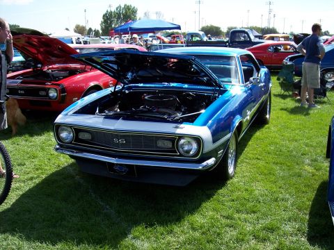 1972 Ford Ranchero - A blue and silver 1969 Chevrolet Camaro SS is displayed with its hood open at an outdoor car show.