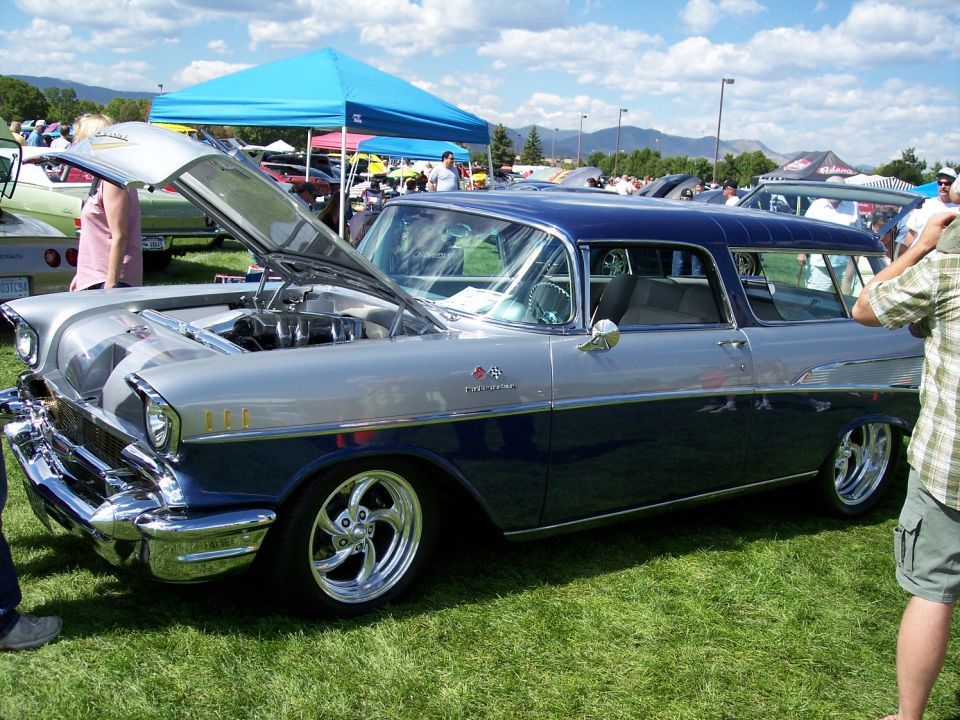 Two-tone blue and silver 1957 Chevrolet Nomad with hood open, chrome wheels, and custom paint