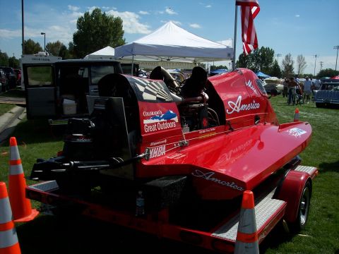 1972 Ford Ranchero - A red racing boat with 'America' written on its side is displayed on a trailer at an outdoor event.