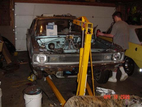 1964 Ford Fairlane - A car's engine is being removed in a garage, with a yellow car parked nearby.