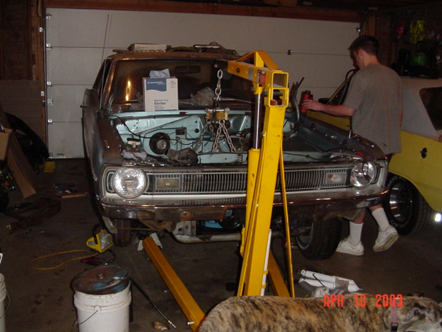 1960s sedan in a garage with hood off and yellow engine hoist chained into engine bay