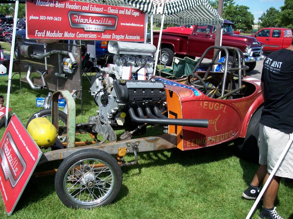 Custom dragster build with a V8 engine, roll cage, and exposed chassis. A Hanksville Hot Rods banner is visible