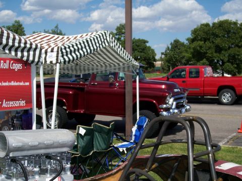 1972 Ford Ranchero - A classic red GMC pickup truck is displayed under a striped awning, with another red truck visible in the background.