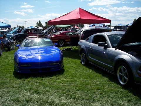 1972 Ford Ranchero - Two cars are parked on a grassy field under a sunny sky with clouds.