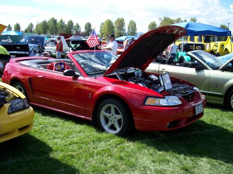 1972 Ford Ranchero - A red convertible sports car is displayed with its hood open at an outdoor car show.