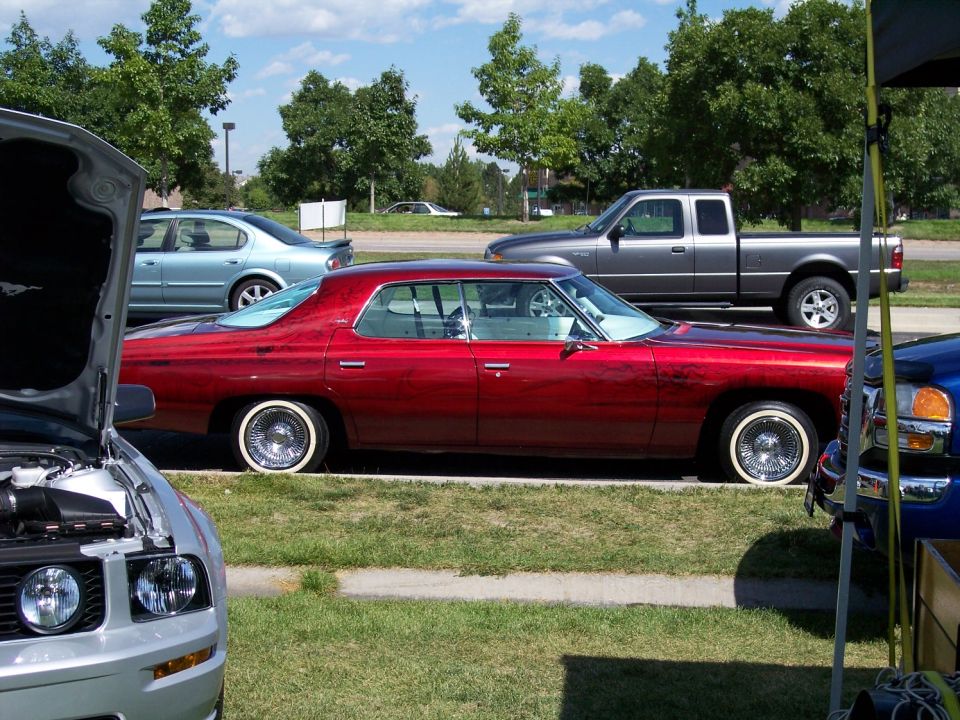 Red 1972 sedan with wire wheels parked next to a pickup truck
