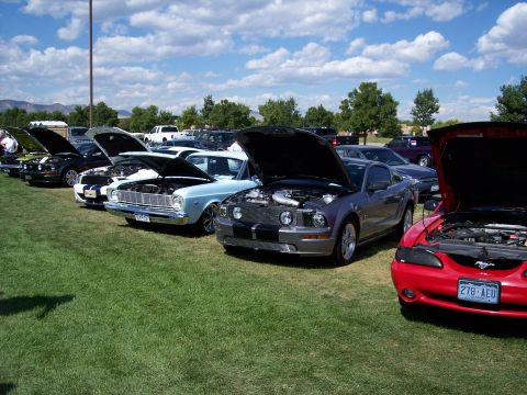 1972 Ford Ranchero - Several cars are parked on a grassy field with their hoods open under a partly cloudy sky.