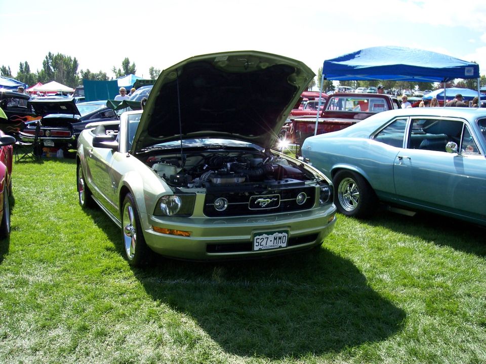 Light green convertible with hood open, showing engine and Mustang emblem