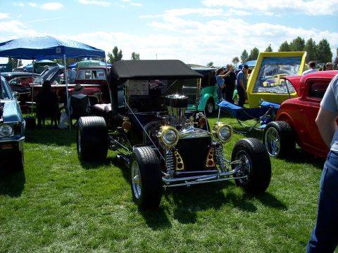 1972 Ford Ranchero - A custom hot rod with a prominent engine and gold detailing is displayed at an outdoor car show.