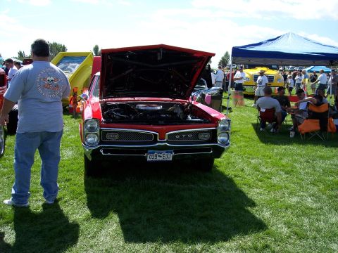 1972 Ford Ranchero - A classic red Pontiac GTO is displayed with its hood up at a car show, with spectators and other vehicles in the background.