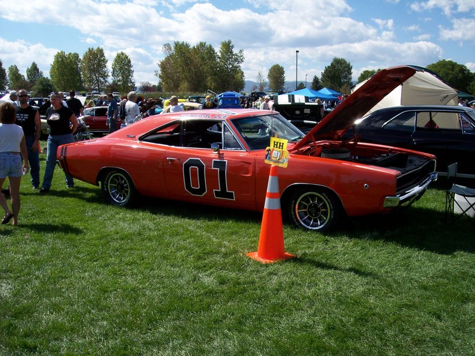 Orange 1969 Dodge Charger with "01" on door, hood open, parked on grass at car show