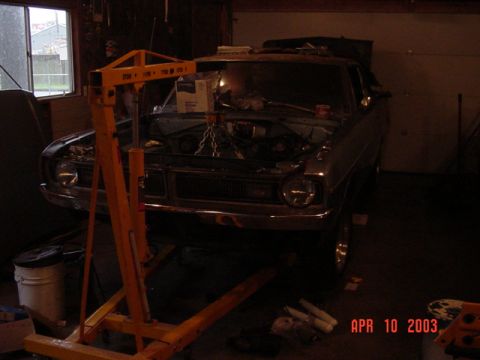 1964 Ford Fairlane - A car is being worked on in a garage, with an engine hoist positioned over the open hood.