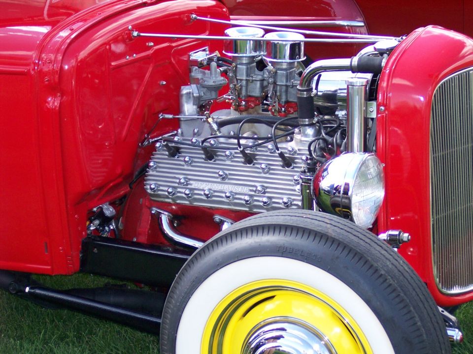 Close-up of a V8 engine with dual carburetors and chrome details on a red hot rod