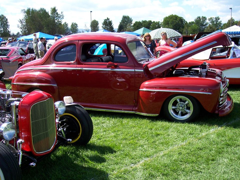 Red coupe with hood open, chrome trim, and custom wheels