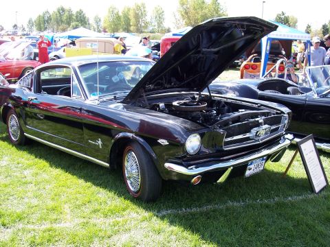 1972 Ford Ranchero - A black 1965 Ford Mustang coupe is displayed with its hood open, its engine and wire wheels.