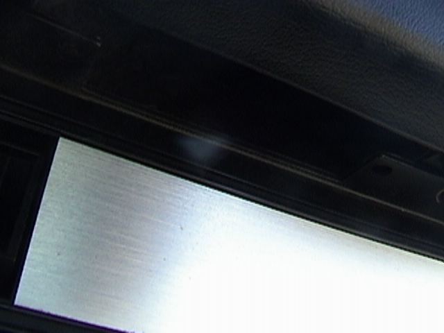 Close-up of a car's interior trim panel showing a brushed metal insert and black textured material