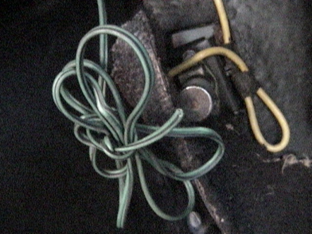 Tangled green and yellow electrical wires, possibly from a vehicle's wiring harness