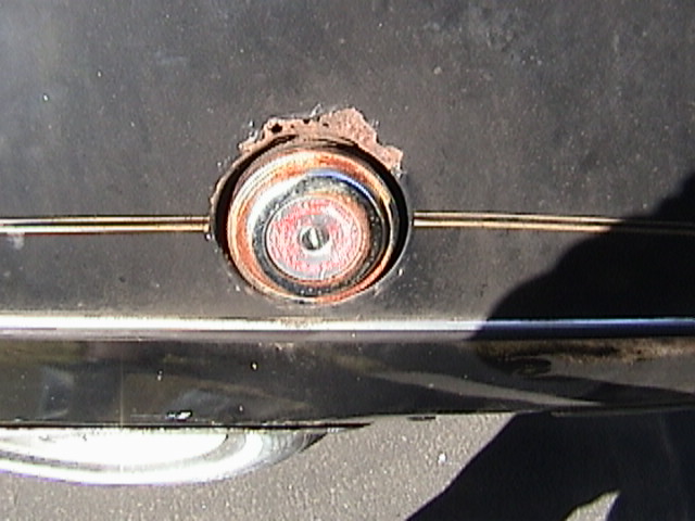 close-up of a rusty fuel filler cap on a dark car body