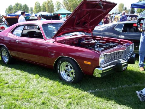 1972 Ford Ranchero - A red 1972 Dodge Dart Swinger is displayed with its hood open, revealing the engine and chrome wheels.