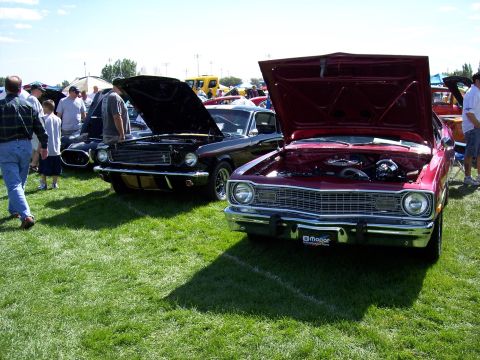 1972 Ford Ranchero - A red 1972 Dodge Dart and a black Ford Mustang are displayed with hoods open at an outdoor car show.