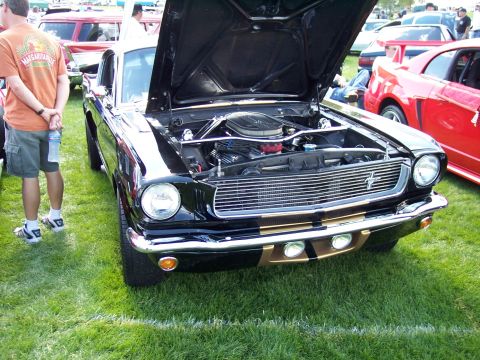 1972 Ford Ranchero - A black classic car, likely a 1965 Ford Mustang, is displayed with its hood open at an outdoor event.