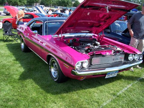 1972 Ford Ranchero - A pink Dodge Challenger is displayed with its hood open, revealing the engine, at an outdoor car show.