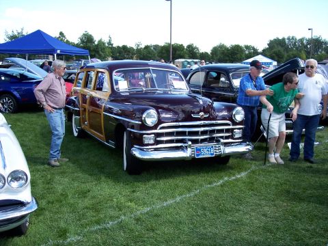1972 Ford Ranchero - A vintage wood-paneled station wagon is displayed at an outdoor car show, with other vehicles and attendees visible in the background.