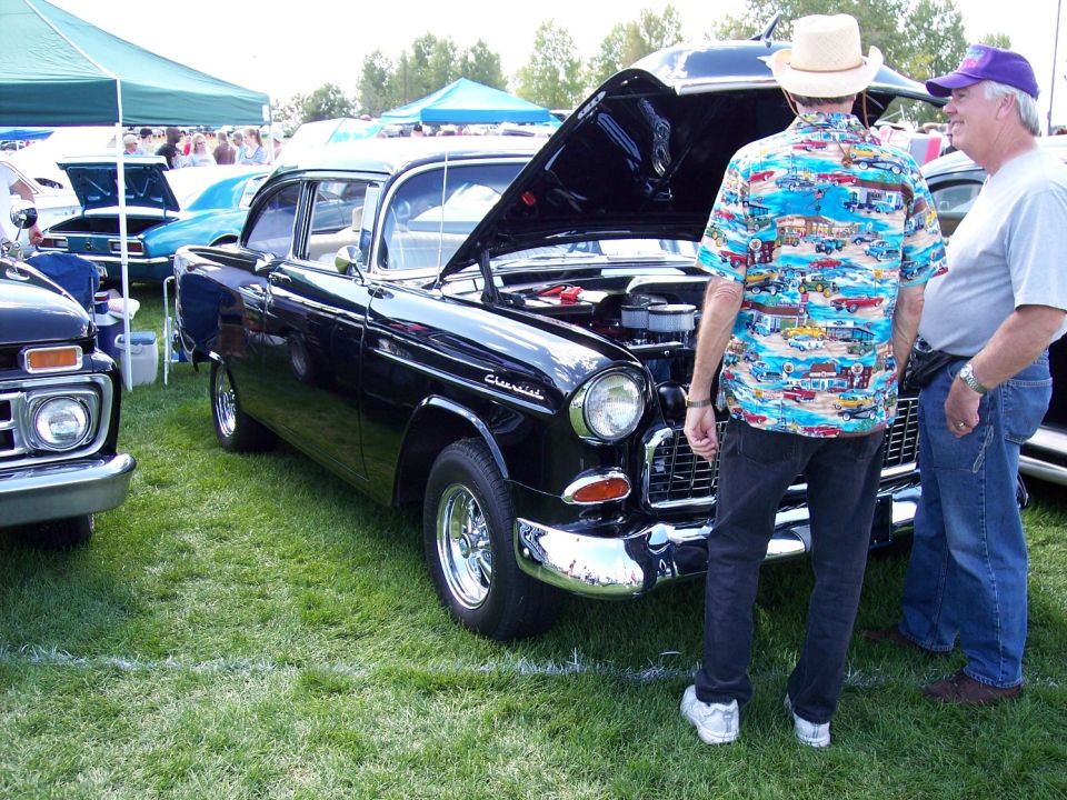 Black 1955 Chevrolet sedan with hood open, chrome bumper, and custom wheels