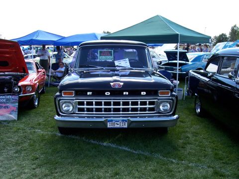 1972 Ford Ranchero - A black Ford pickup truck is displayed at an outdoor car show, with other vehicles and tents in the background.