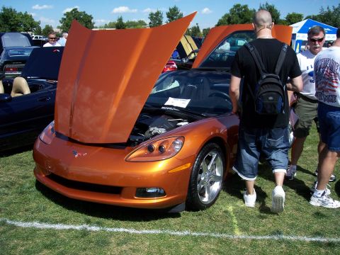 1972 Ford Ranchero - An orange sports car is displayed with its hood open at an outdoor event.