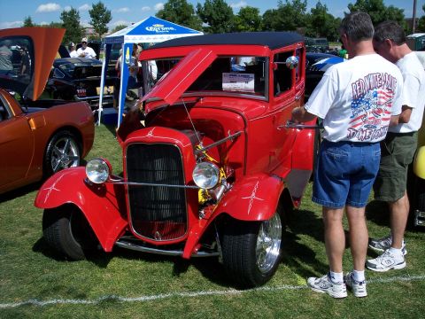 1972 Ford Ranchero - A red vintage coupe is displayed at an outdoor car show with people milling around.