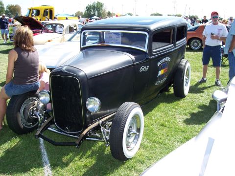 1972 Ford Ranchero - A black hot rod sedan with custom lettering sits on display at an outdoor car show.